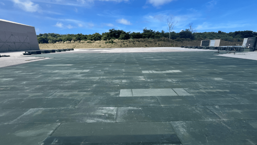 Rectangular green AML panels assembled in a large array over an asphalt concrete surface